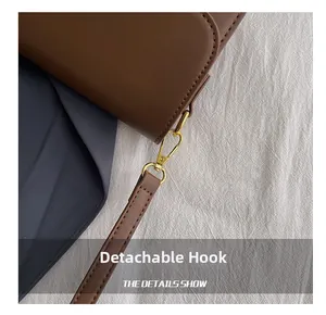 Detailed close-up of golden detachable hook and hardware on brown retro leather handbag