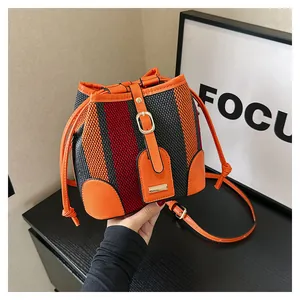 Detail of color-block striped bucket bag with orange leather trim and drawstring