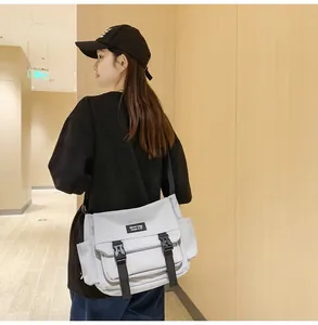 Détail du sac bandoulière gris clair avec boucles noires et poche latérale sur modèle