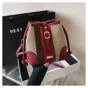 Close-up of the striped woven fabric and red leather trim on this bucket bag detail