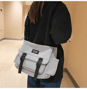 Détail du sac messager gris clair avec boucles doubles et poche latérale pratique