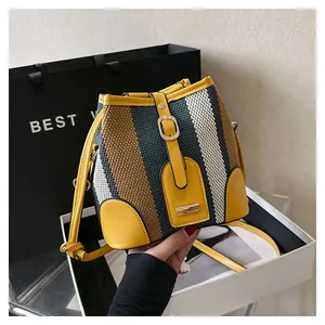 Detail of woven bucket bag featuring vertical stripes and bright yellow leather trim accents