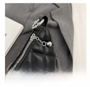 Detail showing smooth silver zipper and metal bead pendant on black quilted handbag