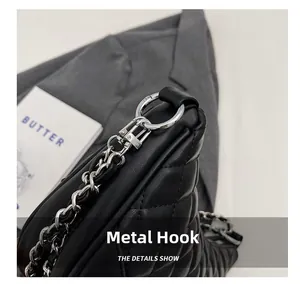 Close-up of silver hardware hook and leather chain on black quilted shoulder bag