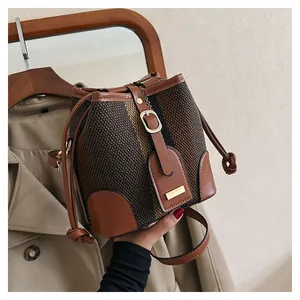 Detail of vintage tweed bucket bag with leather trim and gold hardware in hand