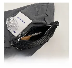 Detail view of black quilted crescent bag with interior pocket showing storage capacity