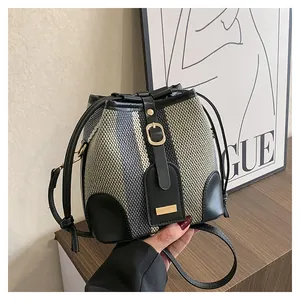 Close-up of striped woven bucket bag featuring black leather trim and drawstring closure