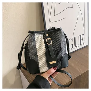 Detail shot of striped knit bucket bag with black leather trim and golden hardware