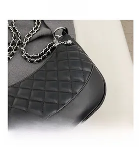 Close-up of black quilted leather texture and woven chain strap of the handbag