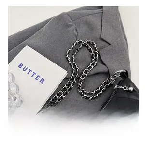Close-up of black quilted shoulder bag with silver chain strap and metal ball detail