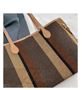 Detail view of large tote bag with striped weave texture and brown leather handle