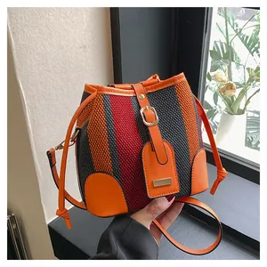 Detail of colorful striped woven bucket bag with orange leather trim and magnetic closure