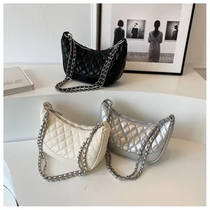 Three quilted hobo bags in black, white, and silver with metal chain straps on display
