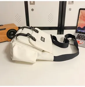 Détail d'un sac messager unisexe blanc avec boucles noires et bandoulière réglable