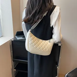 Detailed view of beige quilted crescent bag with silver chain strap worn by a model