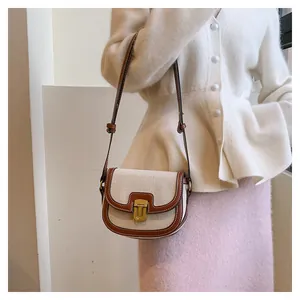 Detail of vintage canvas saddle bag with brown leather trim and golden U-shaped clasp