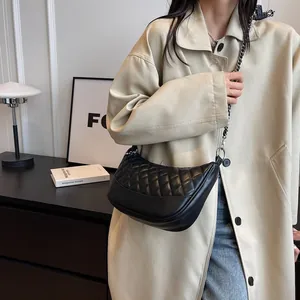 Detail of black crescent shoulder bag featuring quilted lattice pattern and silver chain