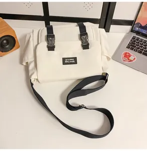 Détail de la besace en toile blanche avec sangles en nylon noir et boucles en plastique