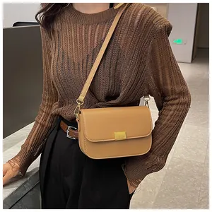 Khaki crossbody bag with gold buckle shown on shoulder of model in casual knitwear