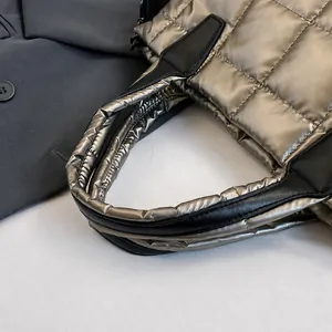 Detailed view of quilted puffer handbag with gold metallic finish and black handles