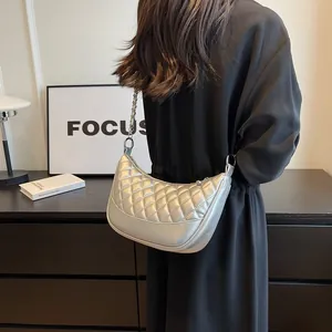 Silver quilted half-moon bag with metallic finish and chain strap shown on model