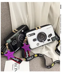 Macro detail of glossy camera-shaped crossbody bags in black and white with smile strap