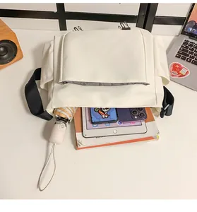 Vue de dessus d'un sac à bandoulière en nylon crème montrant l'espace de rangement principal