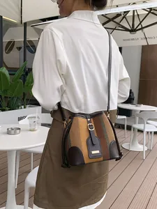 Retro striped woven bucket bag with leather trim shown in an outdoor cafe setting