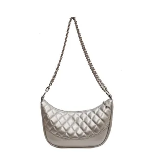 Detail of silver metallic crescent bag with diamond quilted stitching and chain strap