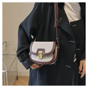 Detail showing the contrast stitch faux leather trim and golden buckle on canvas saddle bag