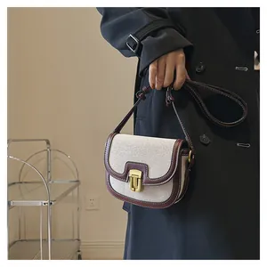 Detail view of the vintage contrast saddle bag with beige canvas and burgundy leather trim