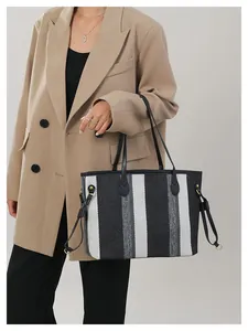 Detail van de grote gestreepte canvas shopper met leren trekkoorden en gouden metalen beslag