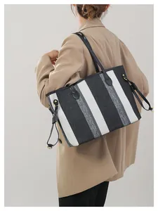Detailweergave van de gestreepte canvas draagtas gedragen met een kaki blazer voor werk
