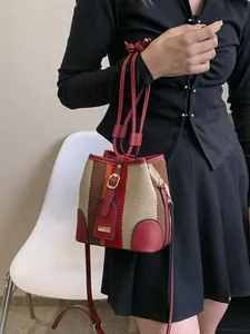 Striped color block bucket bag with red leather straps worn by model on white chair