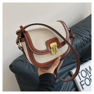 Close-up of saddle bag with beige woven fabric, brown leather trim and golden buckle