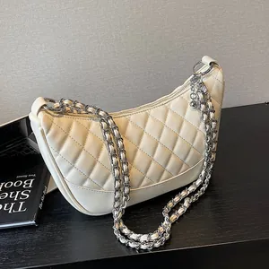 Chic quilted beige hobo bag with silver chain strap and sphere charm on wooden surface