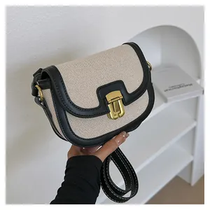 Close-up of contrast stitching on black leather strap and textured fabric saddle bag