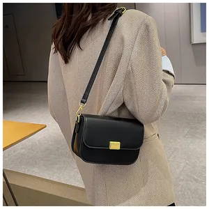 Classic black leather crossbody bag with gold buckle styled with a brown plaid blazer