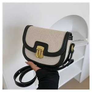 Detail of vintage saddle bag with beige canvas, black leather trim and gold buckle