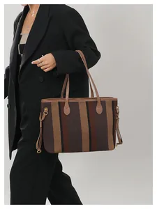 Detailopname van grote gestreepte canvas shopper met leren bies op model in zwarte blazer
