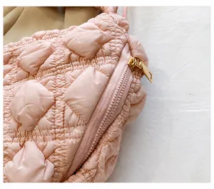 Detalle del bolso acolchado rosa tipo nube con textura suave y cremallera dorada fina