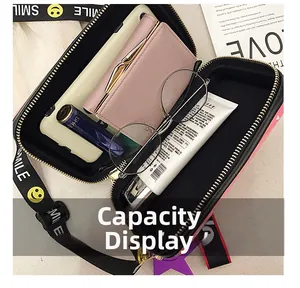Pink crossbody box bag with dual zippers showing interior storage capacity and smiley strap
