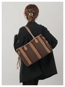 Detail achteraanzicht van gestreepte canvas tote bag met bruine leren handvatten op model