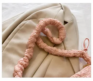 Detalle de bolso nube rosa con textura acolchada y cómoda correa ancha para hombro