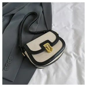Detail of a woven saddle bag featuring black leather trim and contrast white stitching