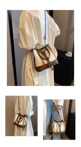 Detail of canvas bucket bag with brown leather stripes and detachable shoulder strap