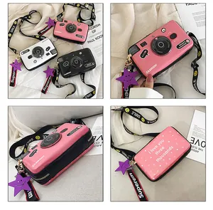 Detail view of mini camera shaped crossbody bags with printed straps in pink white and black
