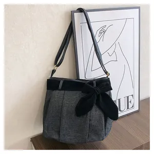Detail of grey felt shoulder bag with a large black velvet bow and golden metal buckle
