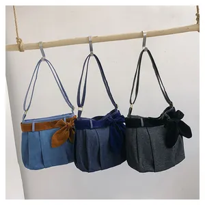Detailed view of canvas crossbody bags in blue and grey with bow accents and pleats