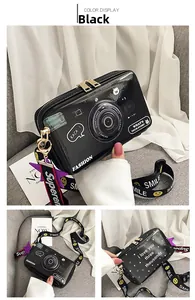 Detail view of black camera-shaped crossbody bag with decorative text and smile strap